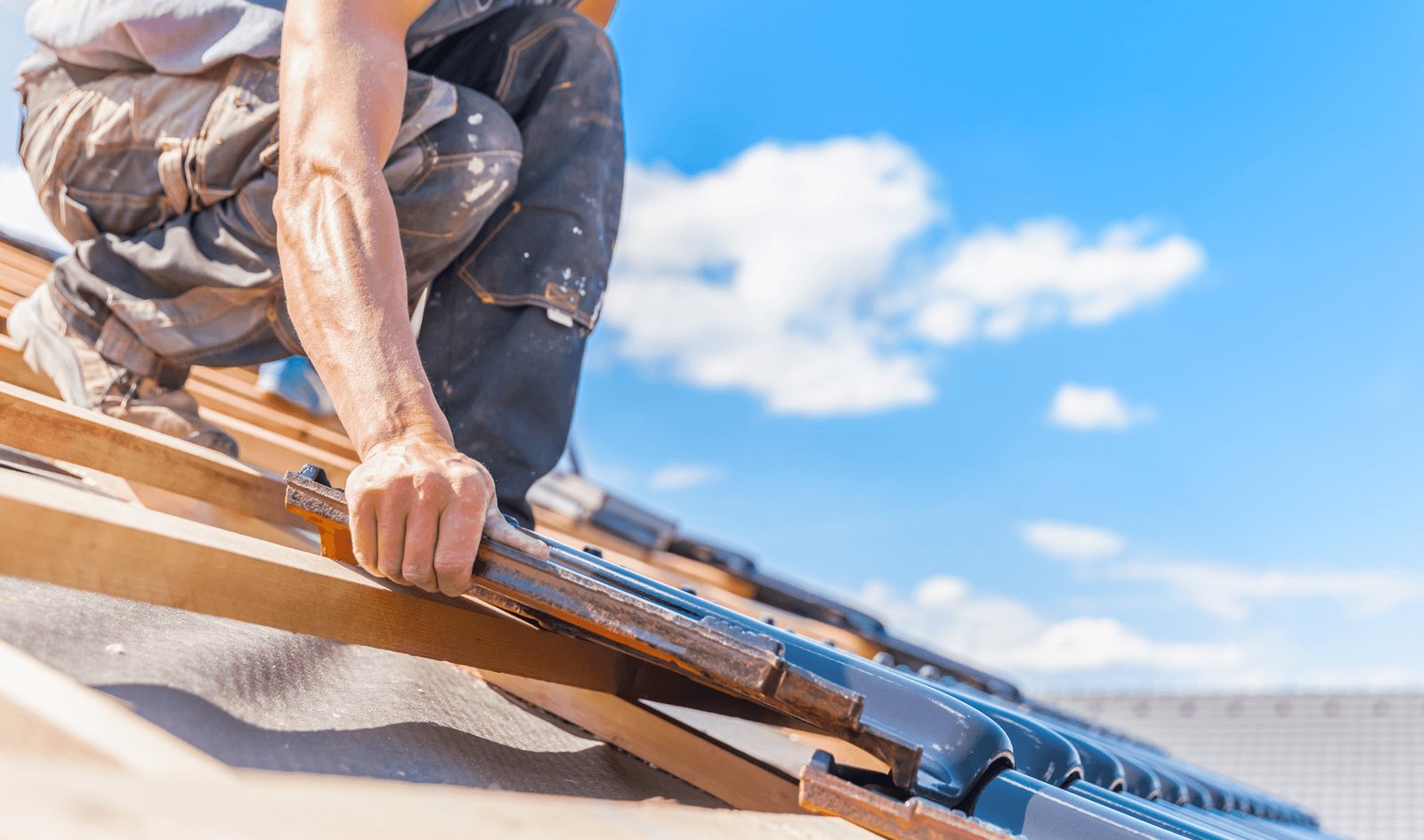 Roofer fitting battens against a blue sky
